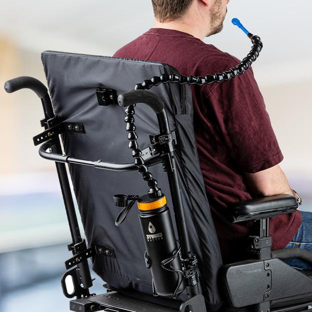 Person with limited mobility using the Giraffe Bottle hands-free Tower XL drinking system with black stainless bottle mounted on a wheelchair